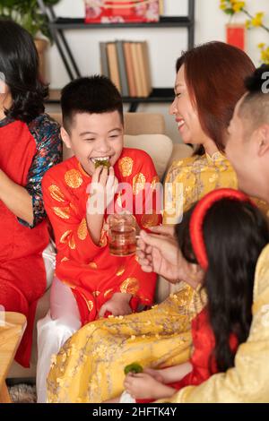 Ragazzo felice premedino godendo kiwi canditi con tè alla festa di Capodanno cinese della famiglia Foto Stock