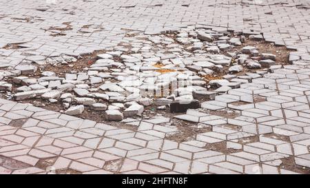 Una strada danneggiata da pioggia e neve, che necessita di manutenzione. Pavimentazione asfaltata rotta con conseguente buche, pericolosa per i veicoli. Foto Stock