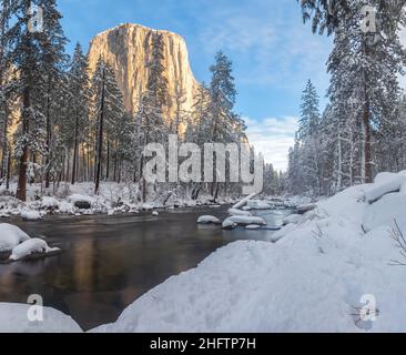 La neve coperte le rocce e la vegetazione lungo il fiume Merced, con il picco El Capitan sullo sfondo, Yosemite National Park, California, USA. Foto Stock