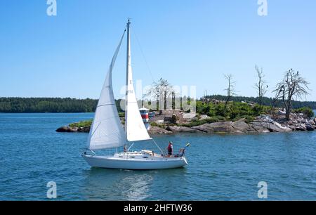 L'uomo e la sua barca a vela, navigando nell'arcipelago di Stoccolma in una bella giornata estiva Foto Stock