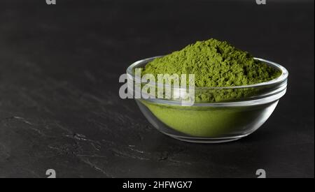 Polvere verde di clorella in una ciotola su sfondo nero di pietra. Polvere di Spirulina o polvere di orzo. Superfood. Spazio per il testo. Foto Stock