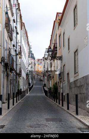 Strada acciottolata che conduce in un quartiere collinare allineato con edifici residenziali a Lisbona Portogallo Foto Stock