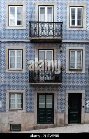 Dettagli architettonici primo piano della tradizionale facciata a muro di piastrelle blu dell'edificio di appartamenti con balconi ringhiera in ghisa e fioriere a Lisbona P. Foto Stock