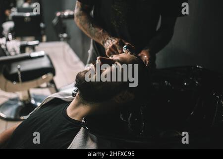 Giovane cliente uomo al barbiere ottenere haircut Hipster lavaggio capelli Foto Stock