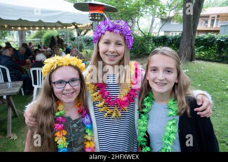 Tre cugini che indossano i leis colorati in posa e godendo la festa di anniversario del nonno tenuta nel loro cortile. Minneapolis Minnesota, Stati Uniti Foto Stock