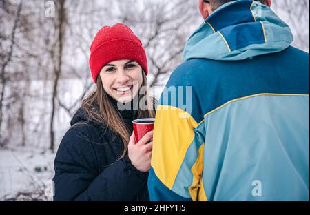 Una giovane donna con un uomo a piedi in inverno con una thermo Cup. Foto Stock