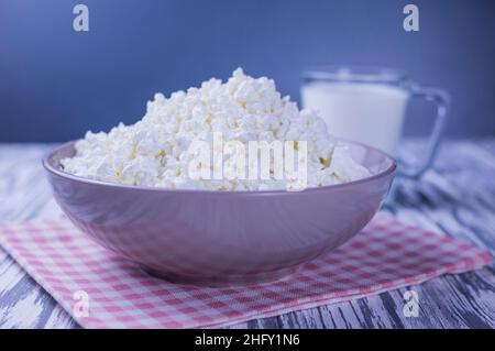 formaggio casolare di latticini in un piatto con un bicchiere di latte su sfondo di legno Foto Stock