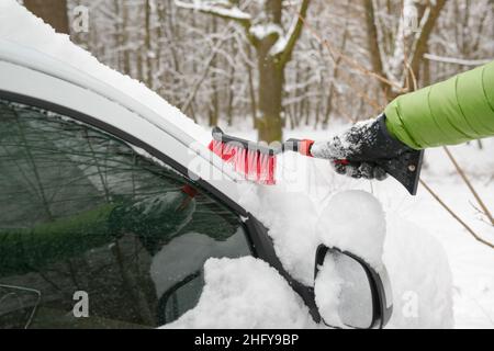 Pulizia dell'auto in inverno neve, mano dell'uomo con una spazzola Foto Stock