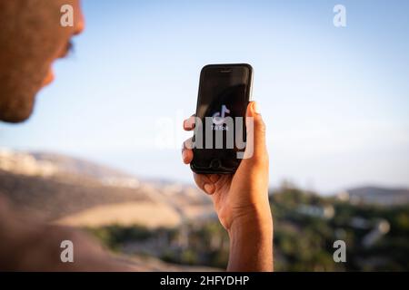 Un ragazzo tiene uno smartphone con il logo TikTok, è un'applicazione molto popolare e un servizio di social networking incentrato sul video Foto Stock