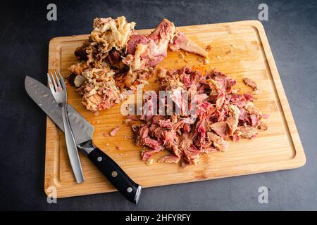 Rimozione della carne da un osso di cetriola bollito: Usando il coltello e la forchetta dello chef per rimuovere la carne da un'ossa di cetriola Foto Stock