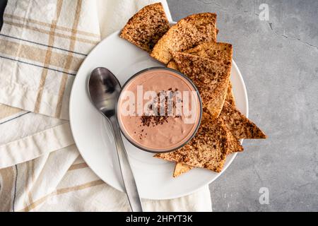 Yogurt al burro di arachidi al cioccolato servito con tortilla Chips al forno: Yogurt al gusto di Cheesecake con scaglie tostate spolverate con cacao in polvere Foto Stock