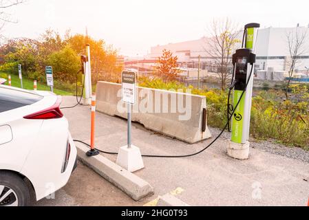 Stazione di ricarica per veicoli elettrici in un parcheggio con una centrale nucleare in background Foto Stock