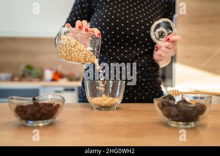 Primo piano sulle mani di sconosciute donne caucasiche che preparano una sana farina d'avena per la colazione a casa Foto Stock
