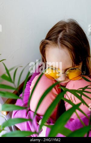 Adolescente ragazza guarda fuori il window.Shadow. Felpa lilla. Foto Stock