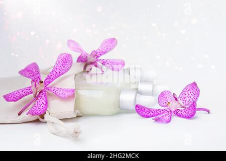 Bottiglie con liquido in un sacchetto e fiori di orchidea Foto Stock