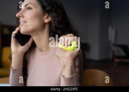 Giovane dipendente sorridente che stringe l'anello di presa, esercitandosi a mano e al polso sul lavoro Foto Stock