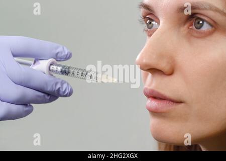 Iniezioni di aumento delle labbra per la donna attraente. Il chirurgo di plastica fa l'iniezione nel labbro in clinica medica. Trattamento viso cosmetico ringiovanente Foto Stock