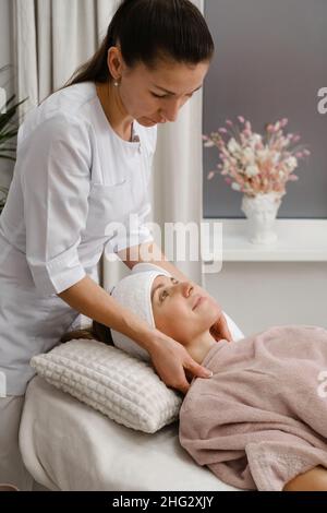 Donna felice al cosmetologo, prima cura e trattamento nella moderna clinica estetica. Donna che si rilassa nel salone di bellezza. Cliente sorridente con Foto Stock