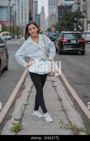 Scatto verticale di una ragazza caucasica (bianca) in posa per la fotocamera al di fuori degli Stati Uniti Foto Stock