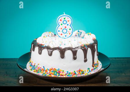 Una torta di compleanno porta una candela nella forma del numero 8. Foto Stock