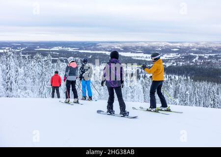 Vuokatti, Finlandia - January2022: Sciatori e snowboarder in cima alla collina che si preparano a sciare lungo la pista di Vuokatti. Foto Stock