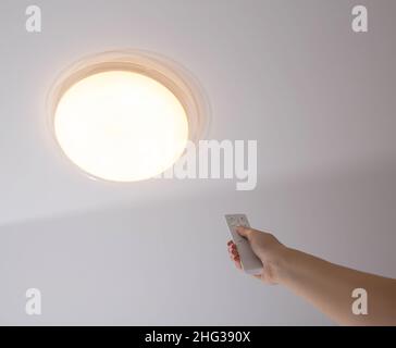 Moderno lampadario a soffitto a LED con pannello di controllo spento. Regolazione della luminosità dell'illuminazione nella stanza Foto Stock