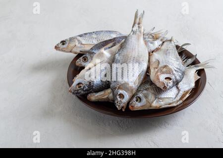 Pesce di fiume salato essiccato in una ciotola su un fondo di calcestruzzo chiaro. Foto Stock