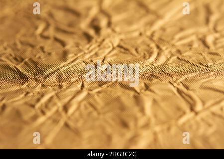 vista dall'alto dettaglio primo piano della carta da imballaggio testurizzata lamina d'oro con superficie rugosa e profondità di campo poco profonda Foto Stock