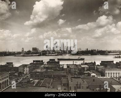 Foto d'epoca dello skyline di Detroit. Skyline di Detroit e barche sul fiume Detroit come visto da Windsor, Ontario(?). In primo piano, i tetti dell'edificio Foto Stock