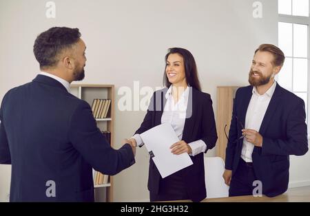 Clienti felici che si scambiano la stretta di mano con avvocato professionale o consulente finanziario Foto Stock