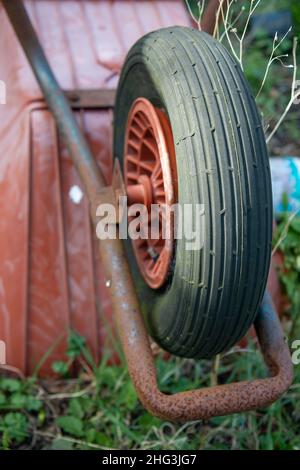 Un vecchio Rusty Wheelbarrow abbandonato capovolto in un giardino Foto Stock