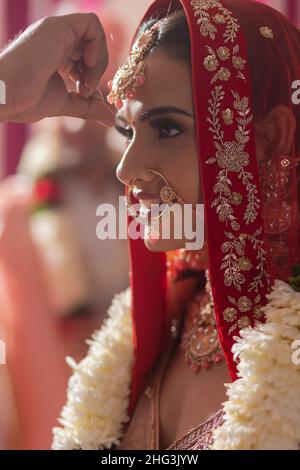 Lo sposo indiano che mette sindoor sulla fronte delle spose durante la cerimonia nuziale Foto Stock