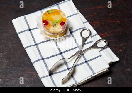 Torta con gelatina, kiwi, ciliegie e mango sul tavolo. Mini dessert yummy su sfondo di legno, primo piano. Foto Stock