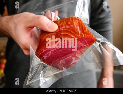 Un uomo che tiene un pesce rosso in un pacchetto. Foto Stock