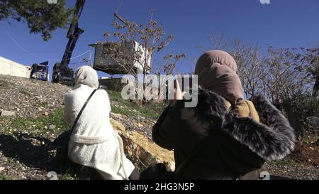 Gerusalemme, Israele. 17th Jan 2022. Le donne palestinesi guardano una gru che solleva una struttura al composto della casa di famiglia di un palestinese, Salhiya, che è richiesto essere liberato nel quartiere Sheikh Jarrah il 17 gennaio 2021 a Gerusalemme, Israele. La famiglia di Salhiya si trova di fronte a una minaccia di sfratto dal 2017, quando la terra in cui si trova la sua casa era destinata alla costruzione scolastica. Il quartiere palestinese di Sheikh Jarrah è attualmente il centro di una serie di controversie di proprietà tra palestinesi e israeliani ebrei di destra. Alcune case erano occupate dai coloni israeliani followi Foto Stock