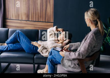 Terapeuta femminile che ascolta e consola una donna che parla di problemi e traumi in officina. Foto Stock