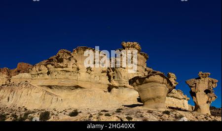 Una vista delle famose erosioni di arenaria e degli hoodoos a Bolnuevo sotto un cielo blu chiaro Foto Stock