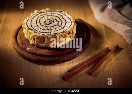 Pannello per torte con torta Esterhazy con cioccolato alle mandorle, massa proteica montata e crema all'olio con aggiunta di cognac su un tavolo di legno. Foto Stock