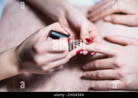 Primo piano immagine del processo manicure, manicurista applicazione gel smalto unghie su unghie femmina. Attenzione all'unghia. Foto Stock