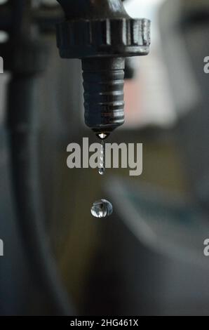 Goccia d'acqua che cade da un rubinetto che gocciola, problemi idraulici e rifiuti d'acqua Foto Stock