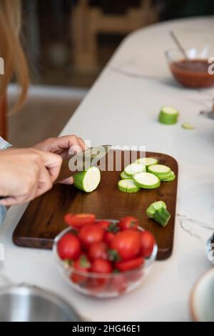 Taglio zucchine. Donna che trita zucchine sul tagliere Foto Stock