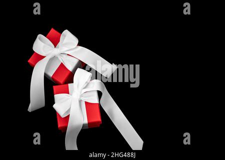 Due scatole regalo rosse con archi bianchi su sfondo nero. Foto Stock