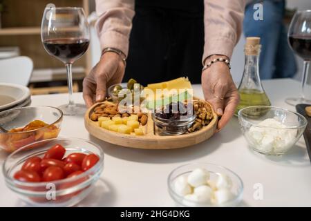 Primo piano di una donna che serve antipasti sul piatto al tavolo da pranzo durante la festa Foto Stock