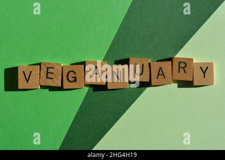 Veganuary, parola in lettere di legno alfabeto isolato su sfondo verde Foto Stock