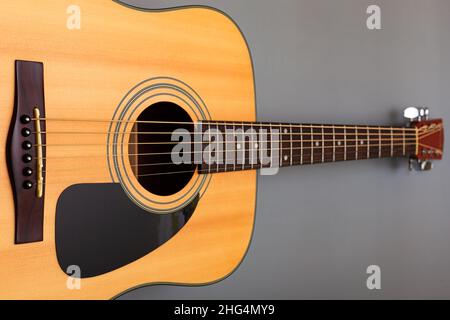 primo piano della tavola sonora superiore di una chitarra acustica gialla su sfondo grigio. Foto di alta qualità Foto Stock