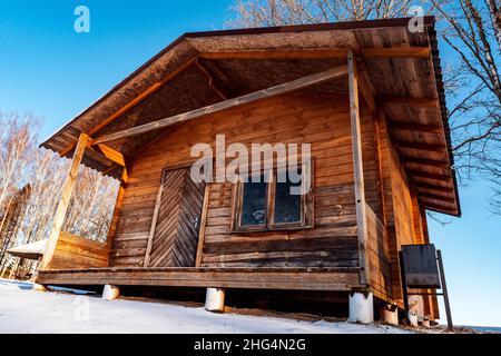 Piccola casa ecologica in legno durante la stagione invernale. Vista ad angolo basso. Foto Stock