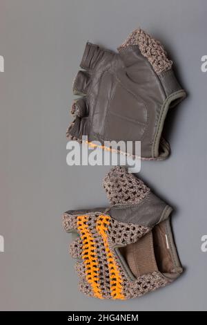 guanti sportivi con dita tagliate con un top intrecciato su sfondo grigio. Foto di alta qualità Foto Stock