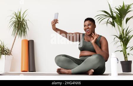 felice bella donna nera chubby prendendo selfie mentre facendo l'allenamento Foto Stock