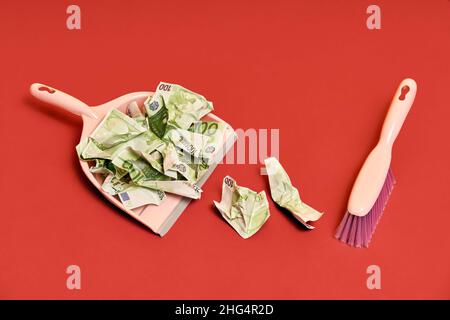 Layout creativo con pattumiera, scopa a mano e fatture in dollari sminuzzate su sfondo rosso. Finanza, corruzione, concetto di attività criminale Foto Stock