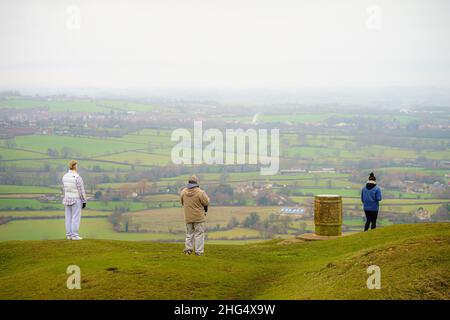 La gente guarda la nebbia rotolare lungo le valli del Cotswold dalla cima del Coaley Peak in Gloucestershire. Data foto: Martedì 18 gennaio 2022. Foto Stock